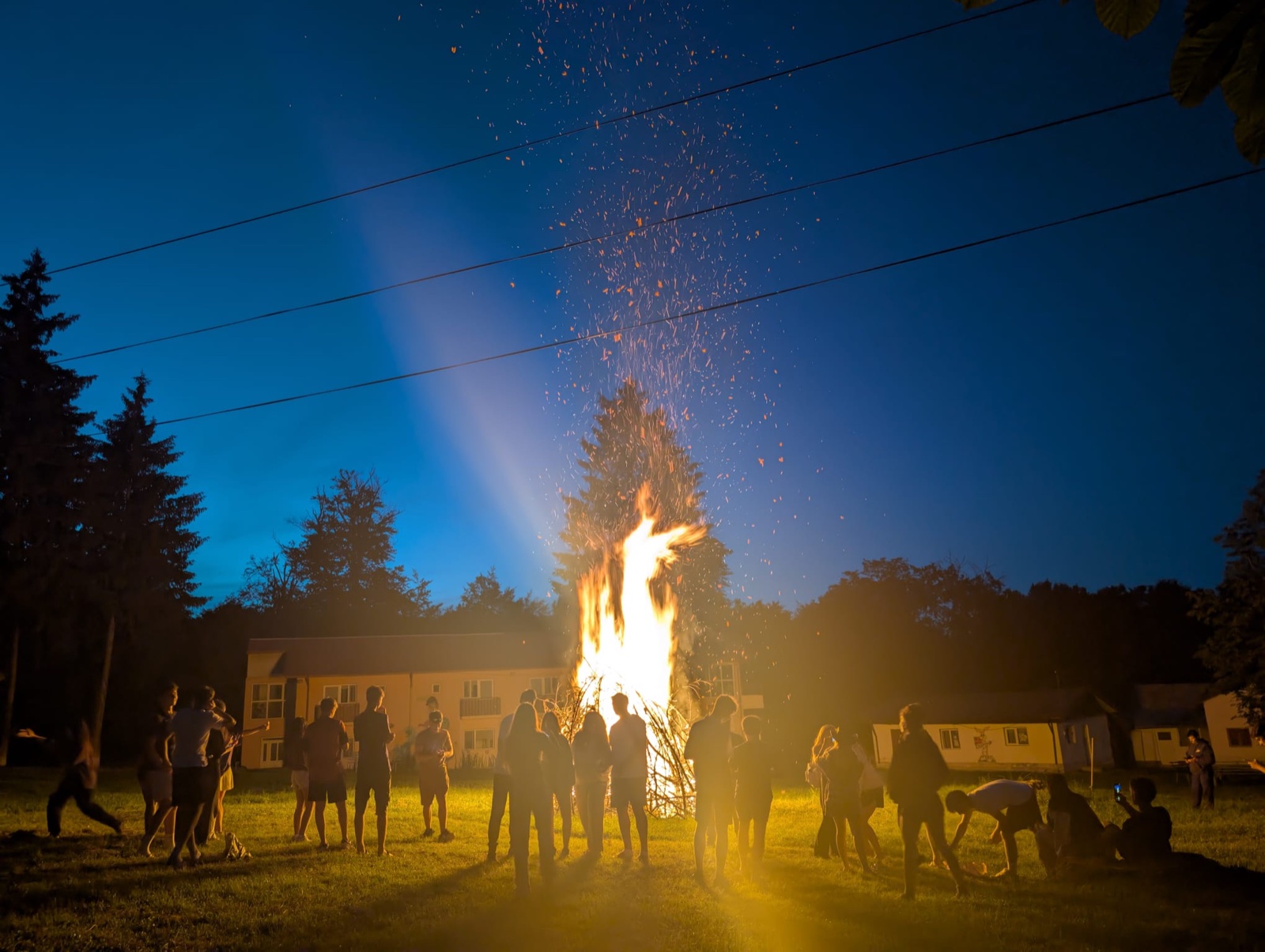 The farewell bonfire sends sparks into the night sky as the group gathers around
