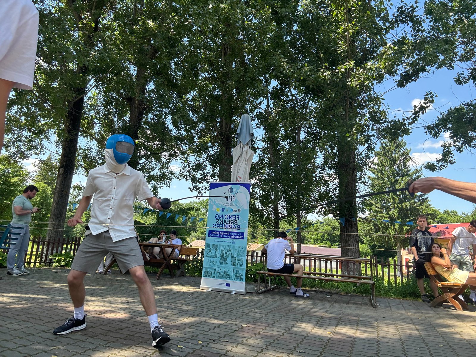 A participant in a fencing mask mid-lunge during the blind fencing try-out