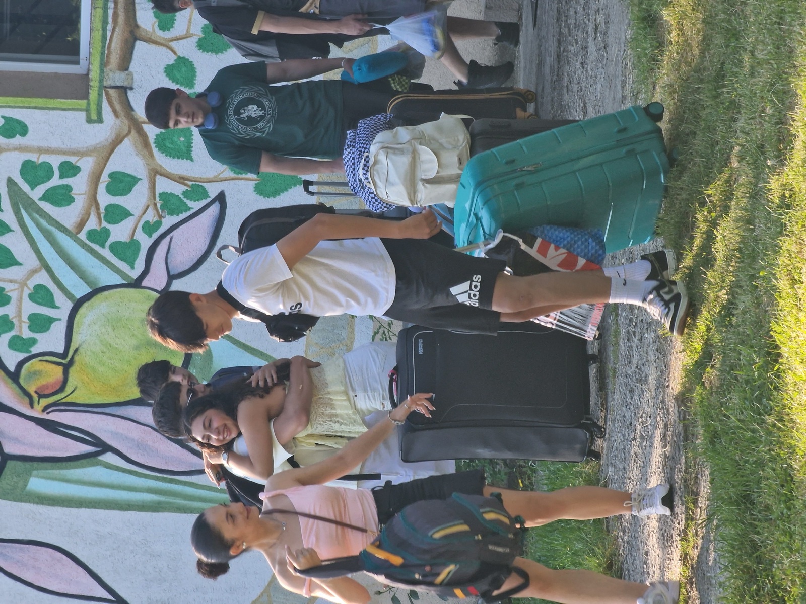 Departure morning: hugs and suitcases in front of the painted villa wall
