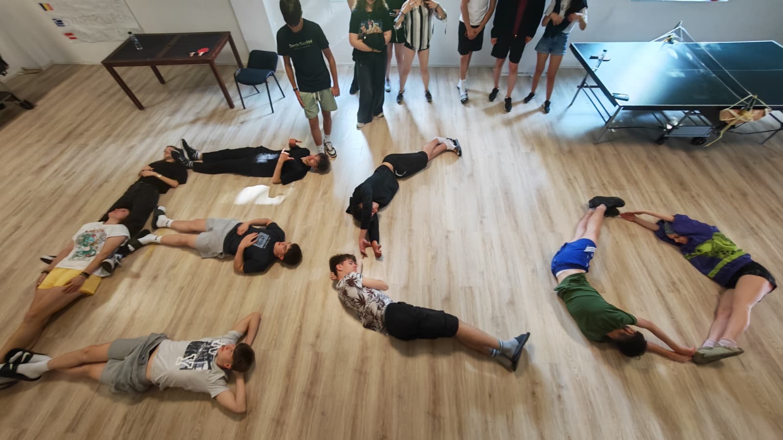 The group lies on the floor spelling ECO with their bodies during Mission Impossible