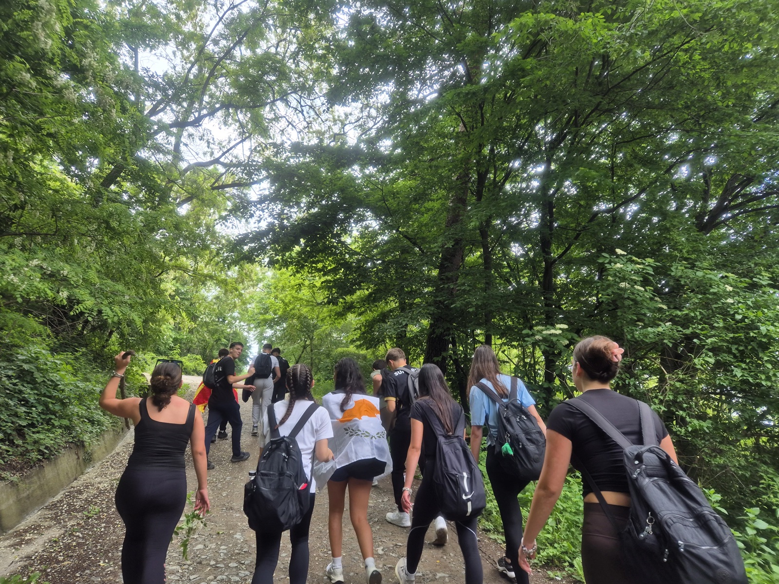 Hikers climb the forest path up Cozla, one wearing the Cypriot flag as a cape