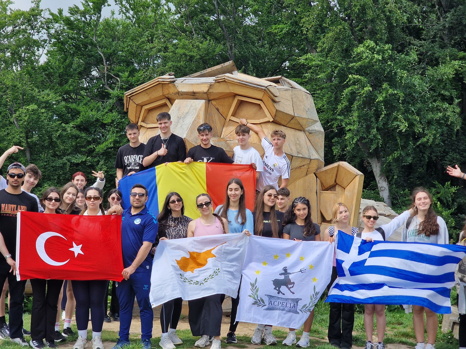Participants holding national flags at the summit troll sculpture on Cozla