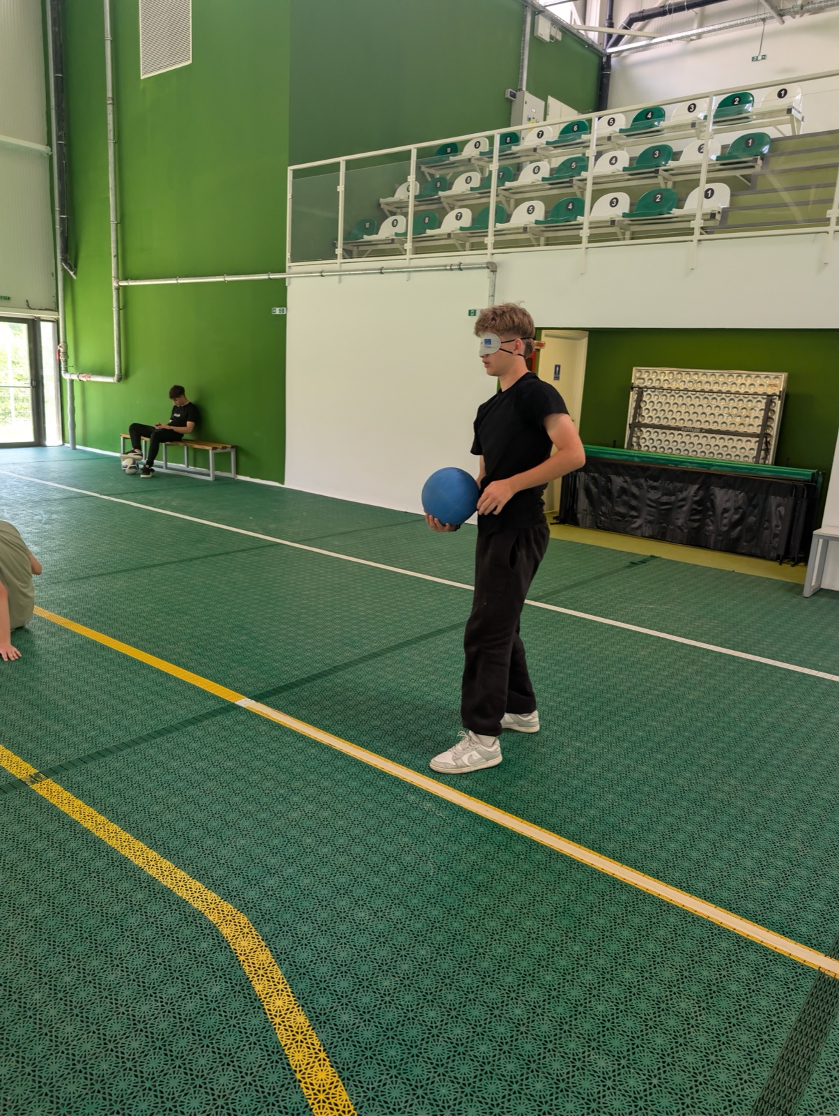 A blindfolded player releases the ball mid-roll during a goalball match