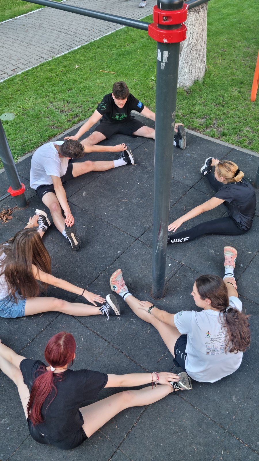 Participants stretch in a circle around the bars, seen from above