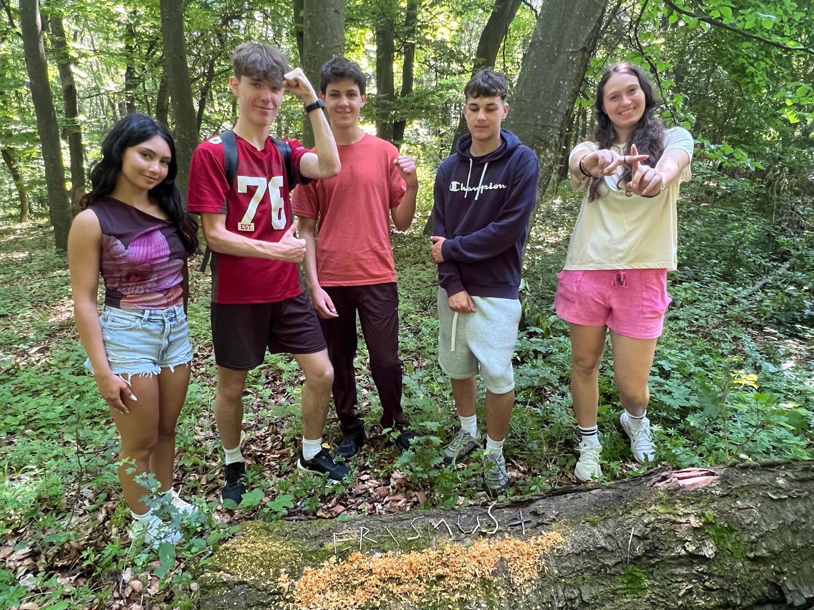 A team poses around ERASMUS+ written in sawdust on a fallen log