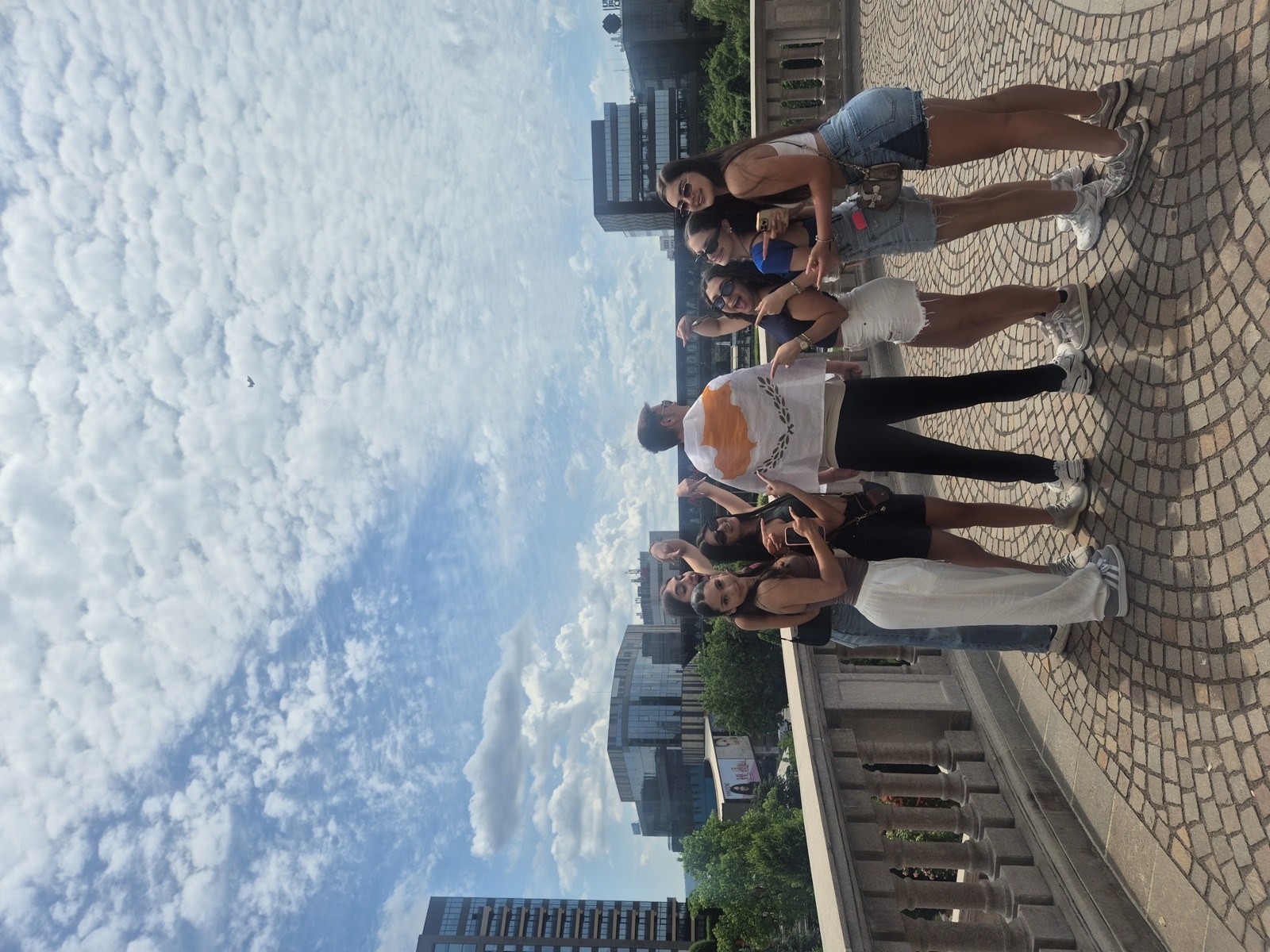 Friends point at the Cypriot flag worn as a cape on a terrace above Iași